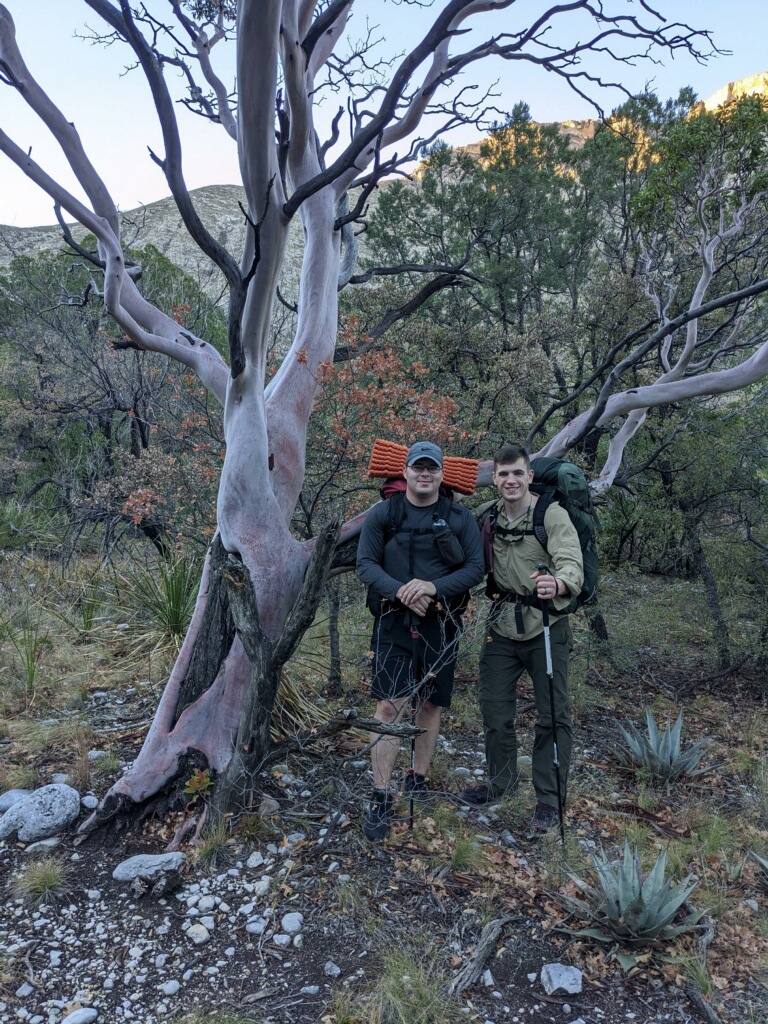 The owners, Jared and Alex, standing under a tree with backpacking gear